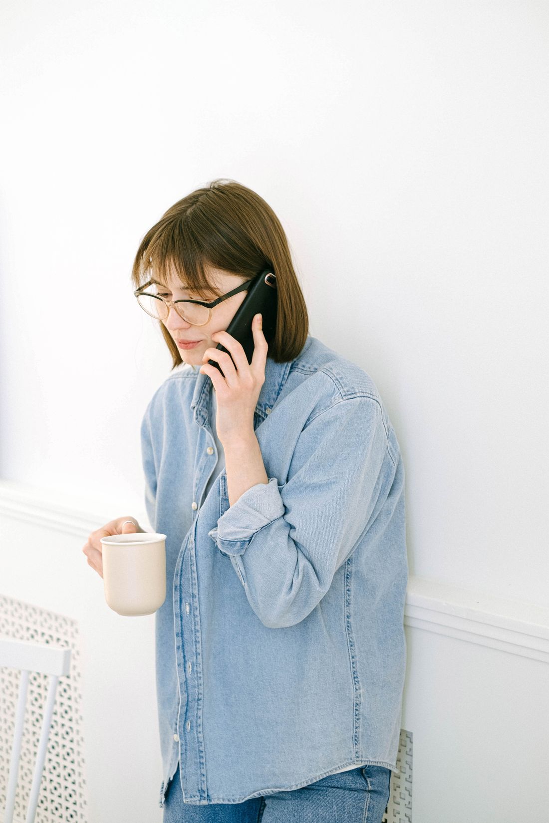 Woman with a coffee talking on her mobile phone at home